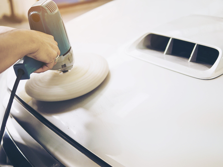Man is polishing car using electric polisher