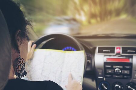 Woman is dangerously looking a map while driving a car