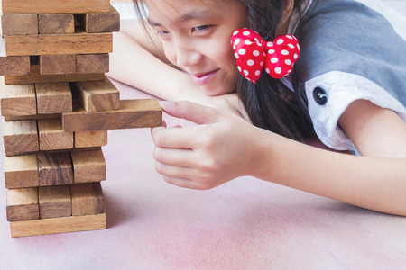 Asian kid is playing wood blocks tower game for practicing physical and mental skillの写真素材