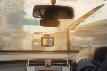 Business man is driving a car in raining day with moving wiper bladesの写真素材