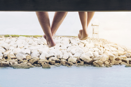 Couple leg hanging happily during their vacation on the sea bridgeの写真素材