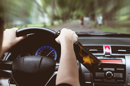 Woman drinking beer while driving a carの写真素材