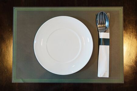 White plate with spoon knife set on a mat in restaurant