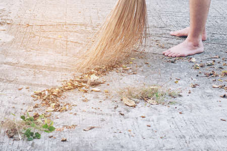 Man cleaning outdoor road using bloom made from dry coconut leave product - local people lifestyle concept in Thailandの写真素材