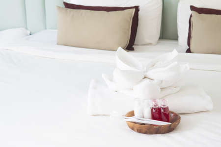 Hotel towel set with toothbrush and toothpaste on white bedの写真素材