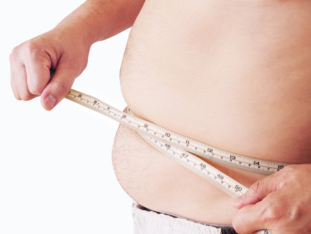 Fat man is measuring his belly using tape meter - dietary health conceptの写真素材