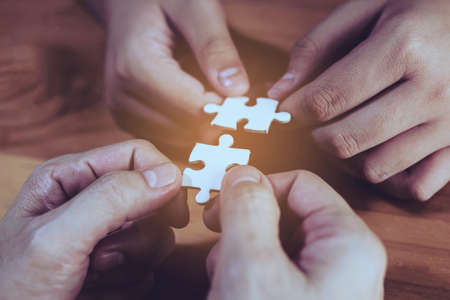 Two hands joining two white jigsaws together