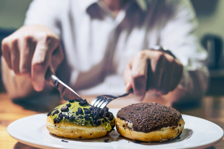 Guy cutting donuts to eatの写真素材