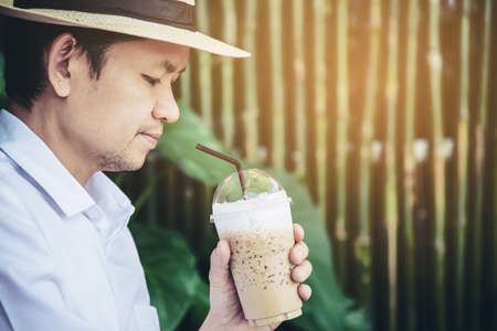 Casual Asian man drink ice coffee happily in nature - people with coffee in nature concept