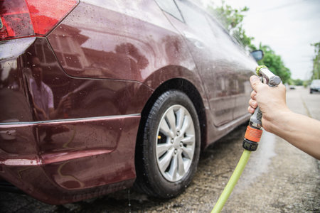 Man washing car using shampoo and water - home people car clean conceptの写真素材