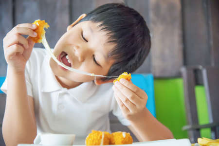 Boy ready to eat sticky stretch fried cheese ball - people and delicious cheese food conceptの写真素材