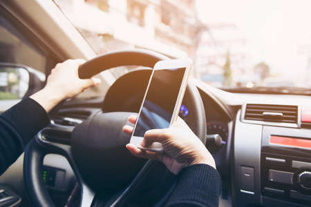 Close up of a woman driving car dangerously while using mobile phone