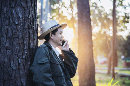 Asian man with mobile phone in forest tree nature - people in spring nature and technology concept
