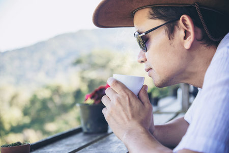 Man drink hot tea with green hill background - people relax in nature conceptの写真素材