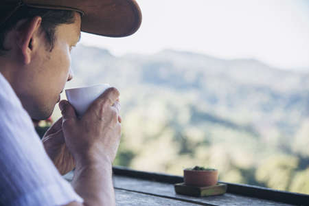 Man drink hot tea with green hill background - people relax in nature conceptの写真素材