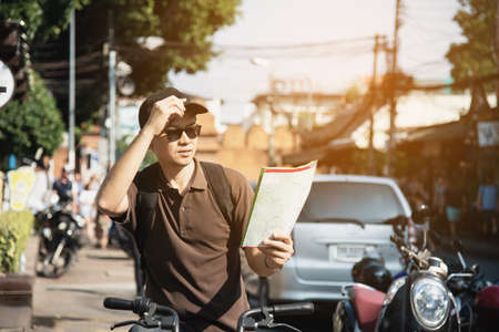 Asian tourist man in a city using bicycle - urban street travel concept