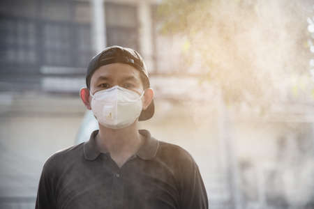 Man wearing mask protect fine dust in air pollution environment - people with protection equipment for air pollution conceptの写真素材