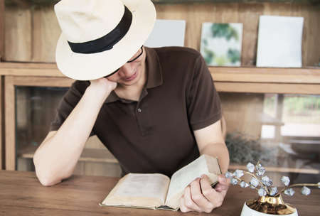 Relax Asian man drink coffee and read book in a modern style coffee shop - people with coffee cup easy lifestyle conceptの写真素材