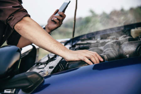 Man try to fix a car engine problem on a local road Chiang mai Thailand - people with car problem transportation conceptの写真素材