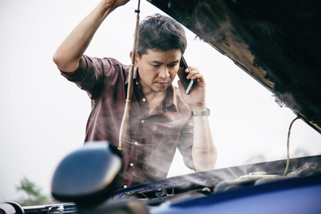 Man try to fix a car engine problem on a local road Chiang mai Thailand - people with car problem transportation conceptの写真素材