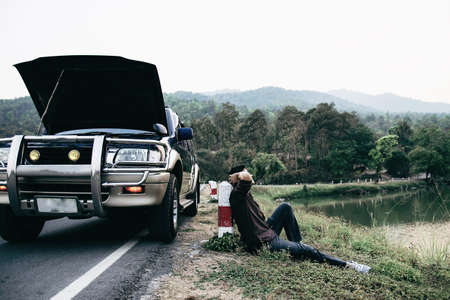Man try to fix a car engine problem on a local road Chiang mai Thailand - people with car problem transportation conceptの写真素材
