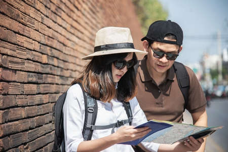 Asian backpack couple tourist holding city map crossing the road - travel people vacation lifestyle conceptの写真素材