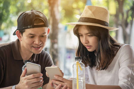 Asian couple enjoy traveling sitting at coffee shop - happy young people on vacation conceptの写真素材