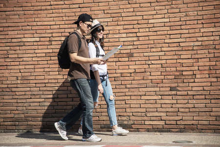 Asian backpack couple tourist holding city map crossing the road - travel people vacation lifestyle conceptの写真素材