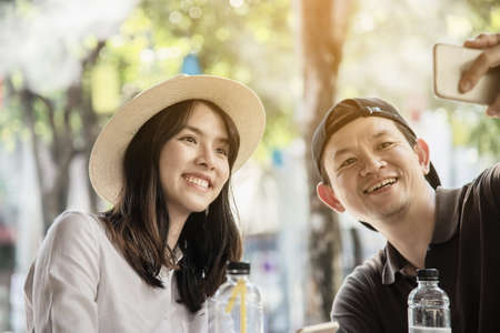 Asian couple enjoy traveling sitting at coffee shop - happy young people on vacation conceptの写真素材