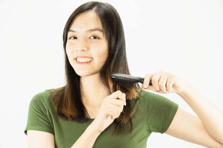 Young beautiful lady happy using comb to straight her hair - woman beauty hair care conceptの写真素材