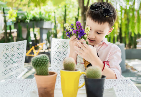 Boy enjoy playing with flower and cactus in a restaurant - boy happy with nature conceptの写真素材