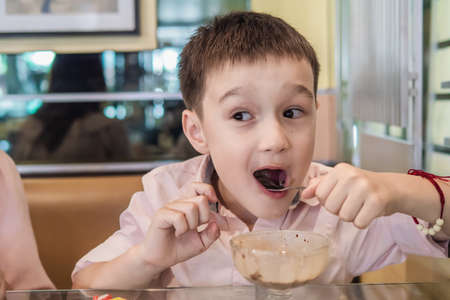 Boy eating chocolate ice cream happily - caucasian boy eat dessert conceptの写真素材