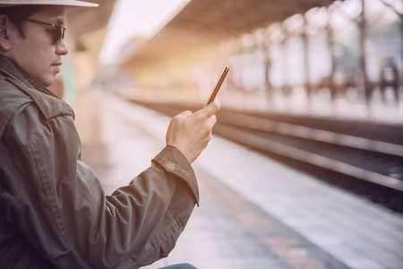 Travel man wait train at platform - people vacation lifestyle activities at train station transportation conceptの写真素材