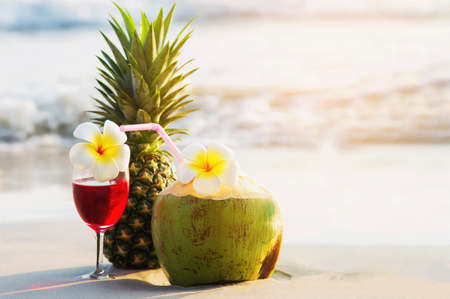 Cocktail glasses with coconut and pineapple on clean sand beach - fruit and drink on sea beach backgroudn conceptの写真素材