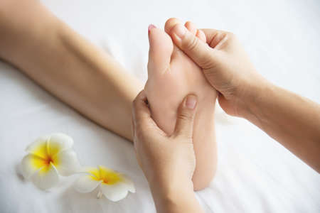 Woman receiving foot massage service from masseuse close up at hand and foot - relax in foot massage therapy service conceptの写真素材