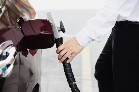 Man is putting NGV, Natural Gas Vehicle, head dispenser to a car at the gasoline station in Thailandの写真素材