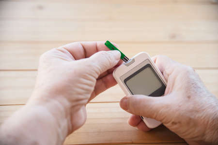 Old lady is testing blood sugar level using blood sugar test kid set - people with medical equipment conceptの写真素材