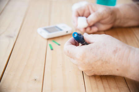 Old lady is testing blood sugar level using blood sugar test kid set - people with medical equipment...