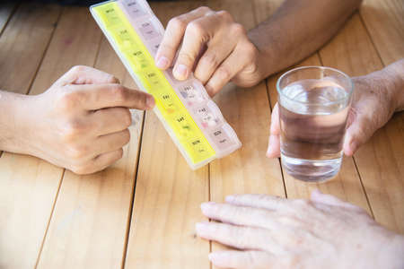 Doctor is assist patient to eat medicine tablet in pillbox correctly - people medical conceptの写真素材