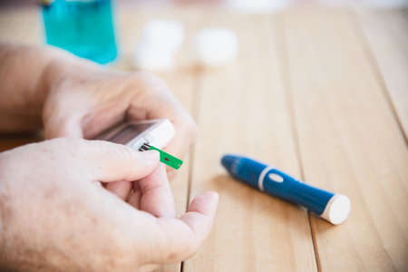 Old lady is testing blood sugar level using blood sugar test kid set - people with medical equipment conceptの写真素材