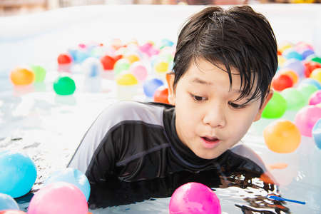 Boy playing with colourful ball in small swimming pool toy - happy boy in water pool toy conceptの写真素材