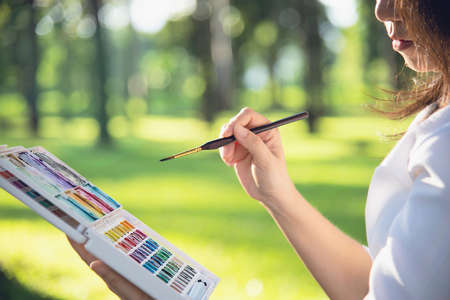 Relax woman painting water colour art work in green garden forest nature - people with creative art in nature stress reduction and meditation conceptの写真素材