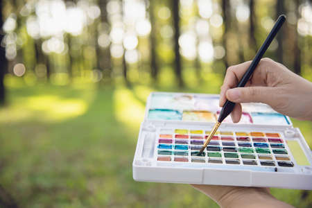 Relax woman painting water colour art work in green garden forest nature - people with creative art in nature stress reduction and meditation conceptの写真素材