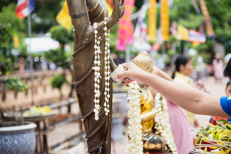 People pouring water onto a Buddha image this is a gesture of worship - people participate the local...