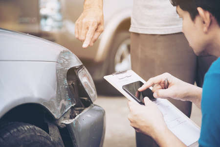 Insurance agent working during on site car accident claim process - people and car insurance claim conceptの写真素材