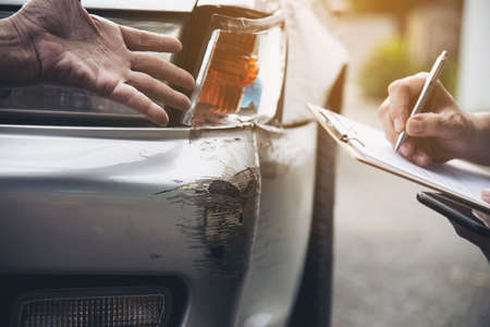 Insurance agent working during on site car accident claim process - people and car insurance claim conceptの写真素材