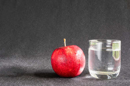 Fresh apple with glass of clean drinking water over gray background - clean fresh fruit and water background conceptの写真素材