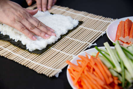 Chef preparing sushi roll over black table background - people with favorite dish Japanese food conceptの写真素材