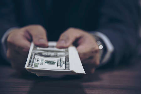 Bank teller man's hands giving dollar banknotesの写真素材