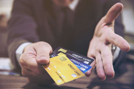 Businessman holding credit cards thinking seriously about payment loan problem - people with...